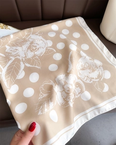 Detail of elegant beige silk scarf featuring white polka dots and camellia patterns
