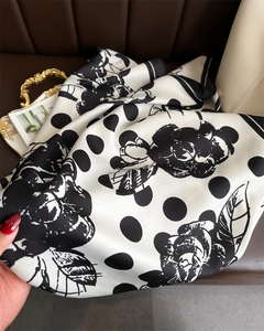 Detail of silk scarf with black rose and polka dot pattern on smooth satin fabric