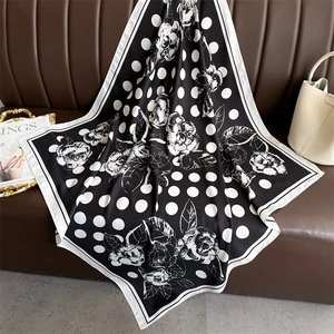 Close-up of a polka dot camellia silk scarf draped elegantly on a leather sofa