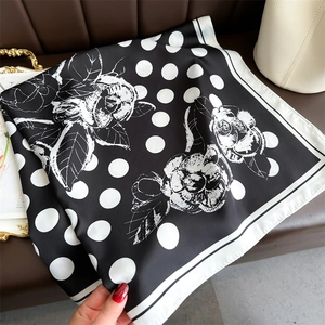 Close-up of silk-like scarf with black and white polka dots and camellia flower print
