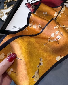 Detailed shot of yellow floral silk scarf with plum blossoms and black stitched edges