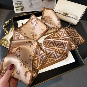 Detail of silk-feel floral scarf with champagne roses on a black luxury tray
