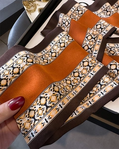 Macro detail of burnt orange floral silk scarf with elegant geometric border