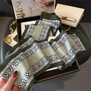 Detailed view of elegant floral silk scarf draped with vintage accessories on a tray