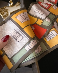 Détail d'un foulard étroit en soie à motifs géométriques et blocs de couleurs vives