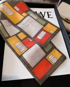 Détail d'un foulard en soie à imprimé géométrique coloré noué sur l'anse d'un sac en cuir chic