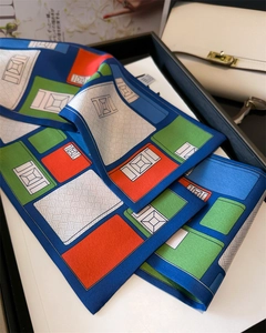 Détail d'un foulard en soie imprimé aux motifs géométriques bleus et verts sur plateau
