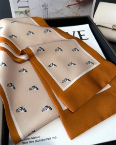 Detail view of floral silk scarf with elegant horse head print on a luxury tray