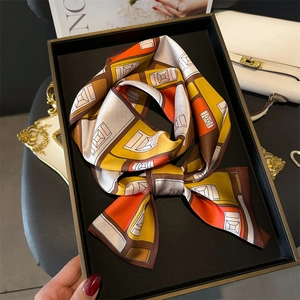 Détail d'un foulard en soie géométrique plié sur un plateau avec accessoires de luxe