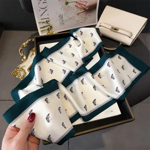 Detail of elegant horse print twilly silk scarf tied on a luxury white handbag