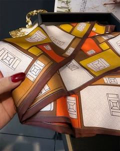Détail d'un foulard en soie à imprimé géométrique, texture satinée et bordure fine