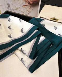Detail of floral silk scarf with horse head pattern and green border on a magazine