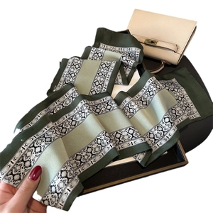 Floral print long silk scarf in dark green and light green folded inside a gift box