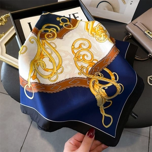 Detail of 100% polyester silk scarf with gold chain and belt print on black tray