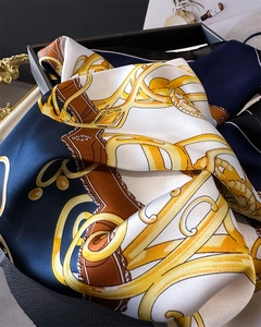 Detail of luxury satin silk scarf with classic horsebit and golden chain patterns