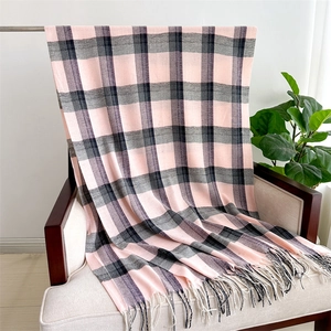 Detail of pink and black plaid cashmere-like scarf with long tassels on a chair