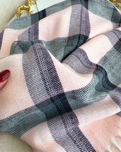 Close-up of pink and grey plaid scarf with soft texture and white tassel details