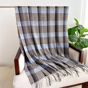 Detail of the soft plaid cashmere-like scarf with fringe edges hanging on a sofa