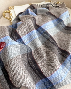 Detail of soft plaid scarf with fringe edge showing thick woven texture and tassels