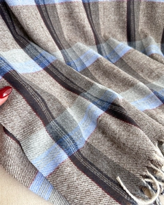 Detail of soft plaid scarf fabric showing blue and brown check pattern and white tassels