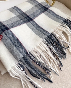 Detailed view of the soft tassels and classic plaid pattern on the cashmere-feel scarf