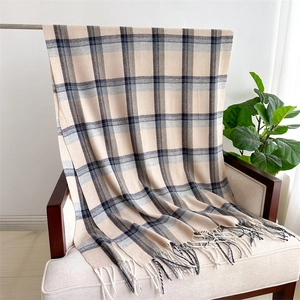 Detail of soft plaid scarf with fringe trim on beige sofa with home decor accents
