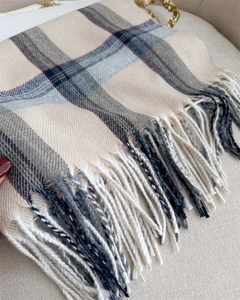 Detail shot of soft beige and grey plaid scarf featuring classic fringe and cashmere-like texture