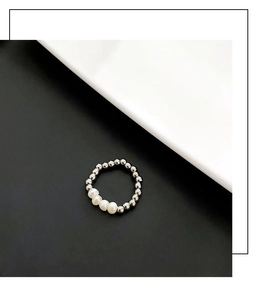 Macro detail of minimalist beaded ring featuring natural white freshwater pearls and silver beads