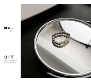 Detailed view of silver beaded ring with three pearls on a reflective mirror base