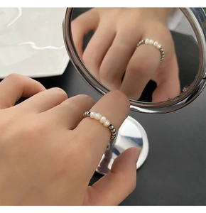 Macro shot of freshwater pearl and silver titanium steel beaded ring on a mirror surface