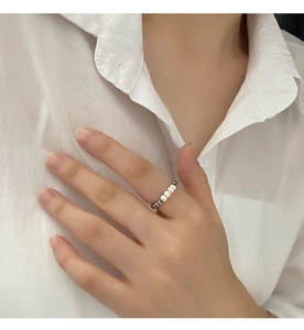 Close-up of minimalist natural freshwater pearl beaded ring on female model's hand