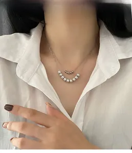Close-up of double-layered silver necklace with metallic beads and faux pearls on model