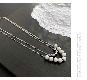 Macro detail of a silver double-layered necklace with metallic beads and white pearls