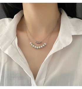 Close-up of double-layered silver chain necklace with grey pearls and metal beads
