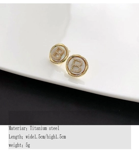 Detailed view of 1.5cm titanium steel gold earrings with B-letter and white shell inlay