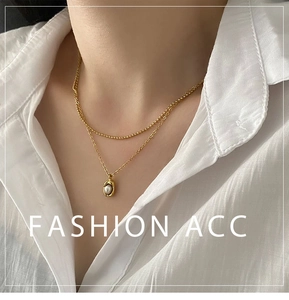 Vue détaillée du collier double rang doré avec pendentif perle et chaîne à perles
