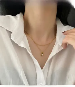 Détail d'un collier doré double épaisseur avec un pendentif perle de lave irrégulier