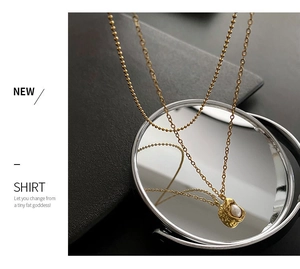 Détail d'un collier doré double épaisseur avec pendentif perle lave sur un miroir rond