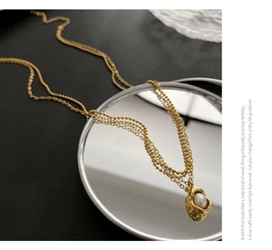 Détail du collier double chaîne doré avec pendentif lave en pois et perle blanche