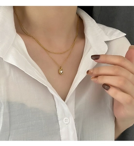 Collier double couche en titane doré avec pendentif perle irrégulière sur le cou du mannequin