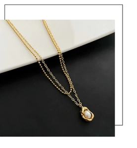 Gros plan d'un collier doré à deux rangs avec pendentif pois et détails en perles