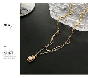Gros plan d'un collier double épaisseur en titane doré avec pendentif perle irrégulière