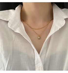 Détail du collier double rang doré avec pendentif perle irrégulier sur mannequin