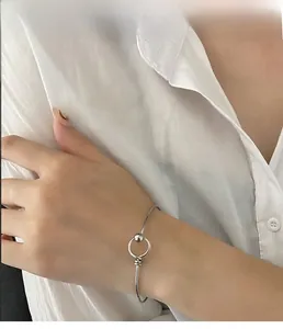 Close-up of minimalist silver titanium steel bangle with ball clasp on model wrist