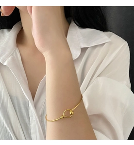 Detail of gold titanium steel bangle with ball clasp closure on a model wrist