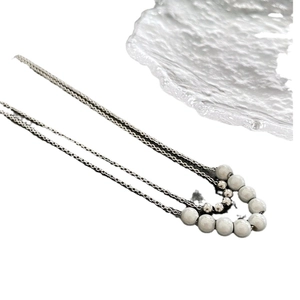 Three-layer silver necklace featuring elegant grey pearls and metallic beads on white