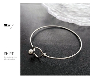 Detail of silver bead pendant and wire wrap closure on a minimalist slim metal bangle