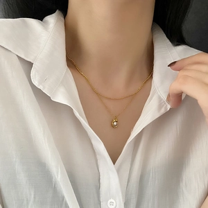 Collier double couche doré rétro avec pendentif perle irrégulière sur chemisier blanc