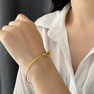 Minimalist gold titanium steel bangle with unique knot design and polished bead for women