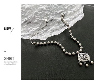 Close-up of silver vintage lock pendant bracelet with beads and small bells on ice texture